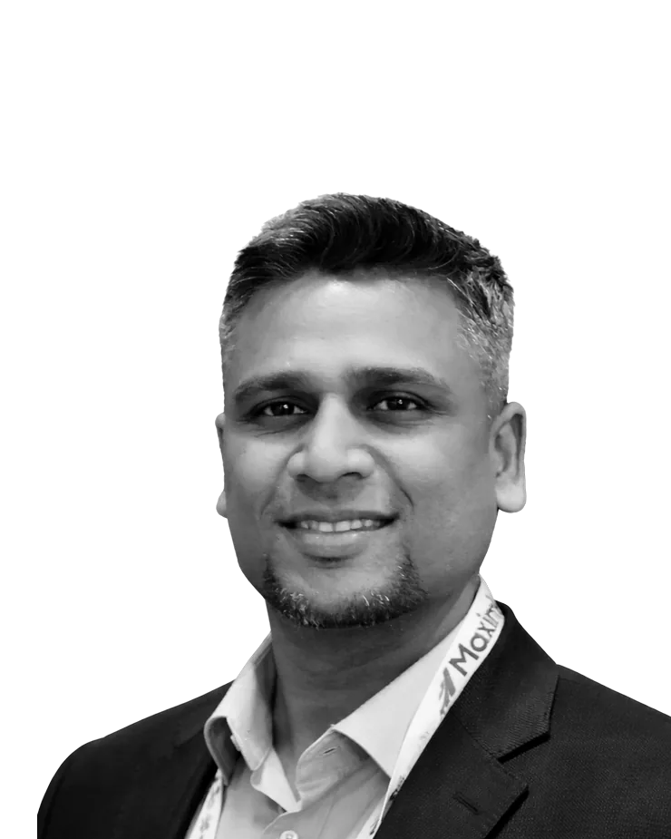 Black and white portrait of Andrew Das, smiling, in a dark suit jacket and open-collared shirt with a conference lanyard.